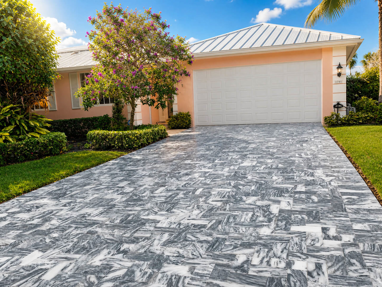 Gray veined marble pavers in herringbone leading to the garage of a coral home on a Boynton Beach lot