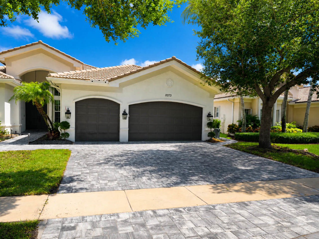 Finished gray paver driveway spanning a three car garage on a Mediterranean style Delray Beach property