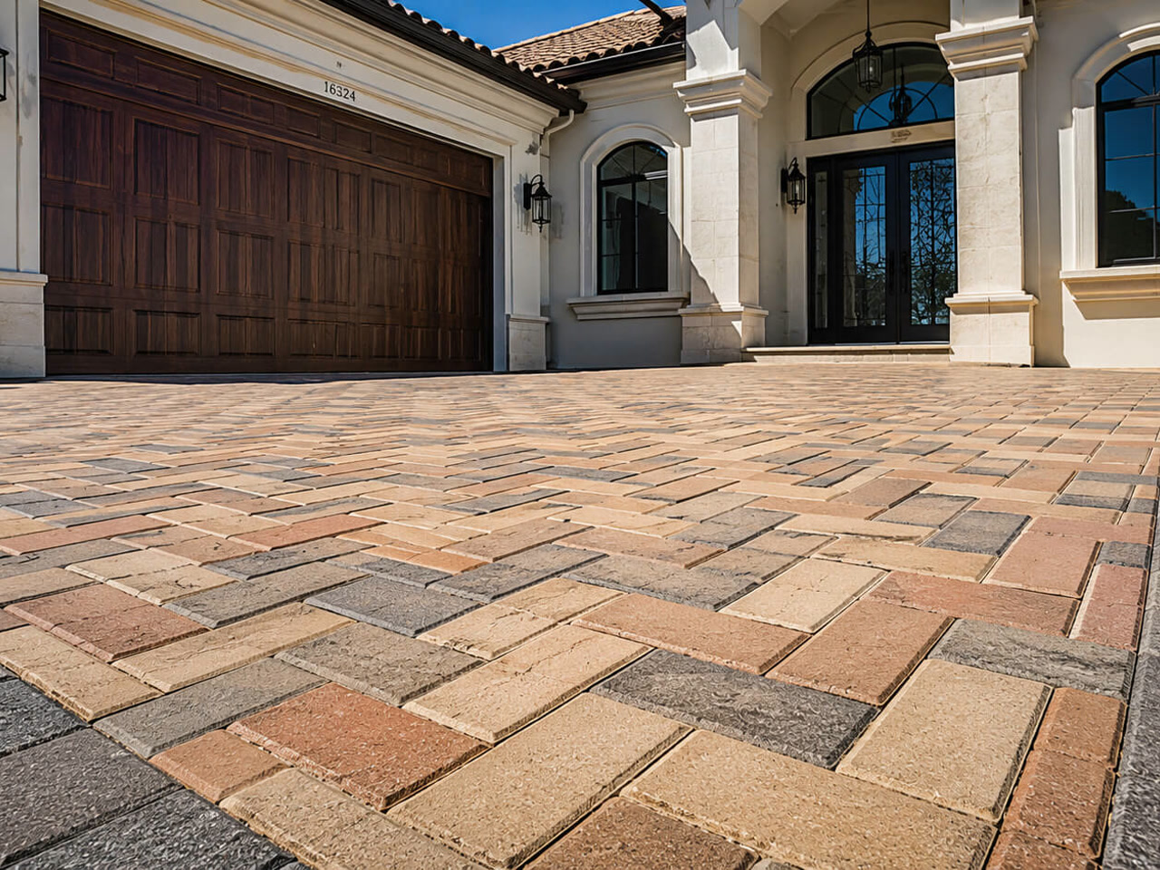 Paver driveway in a blended tan and terracotta herringbone pattern with a charcoal border, leading to a Mediterranean style home at a Wellington residence