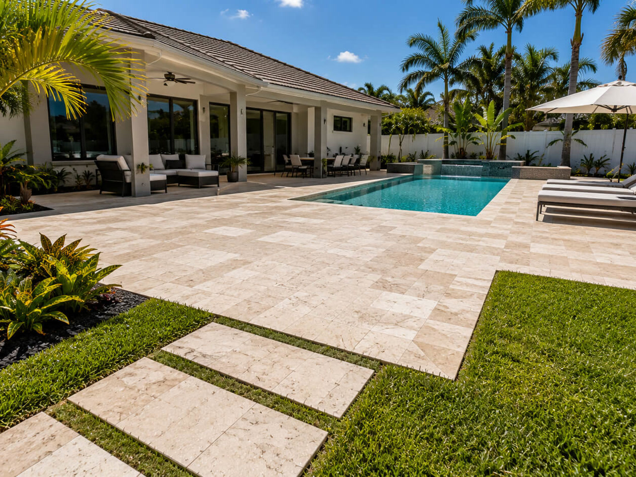 Travertine paver patio and stepping stone walkway leading to the lawn at a Coral Springs pool
