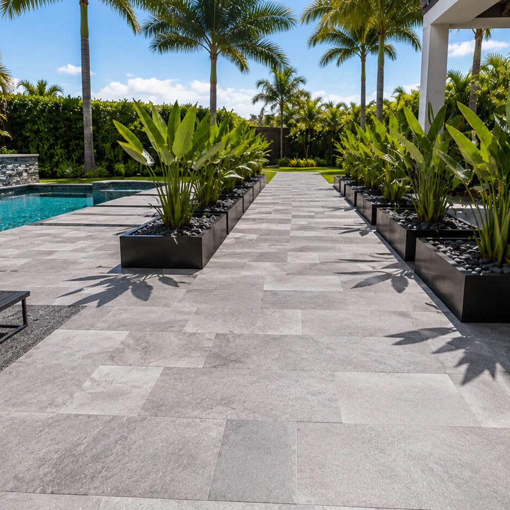 Gray paver walkway between black planters at a Deerfield Beach home, connecting the pool deck to the yard
