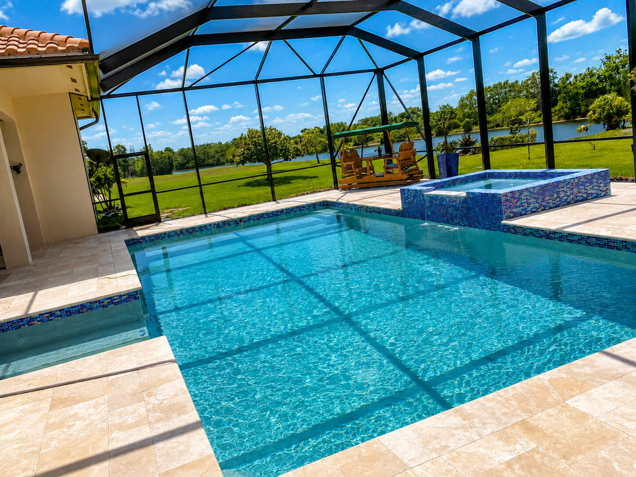 Renovated pool and raised spa with mosaic tile under a screen enclosure in a Jupiter Island backyard