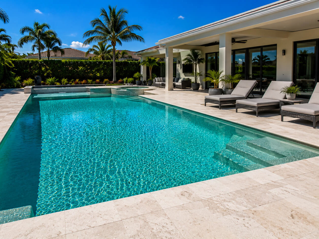 Resurfaced rectangular pool with an integrated spa and travertine deck at a Lake Worth Beach residence