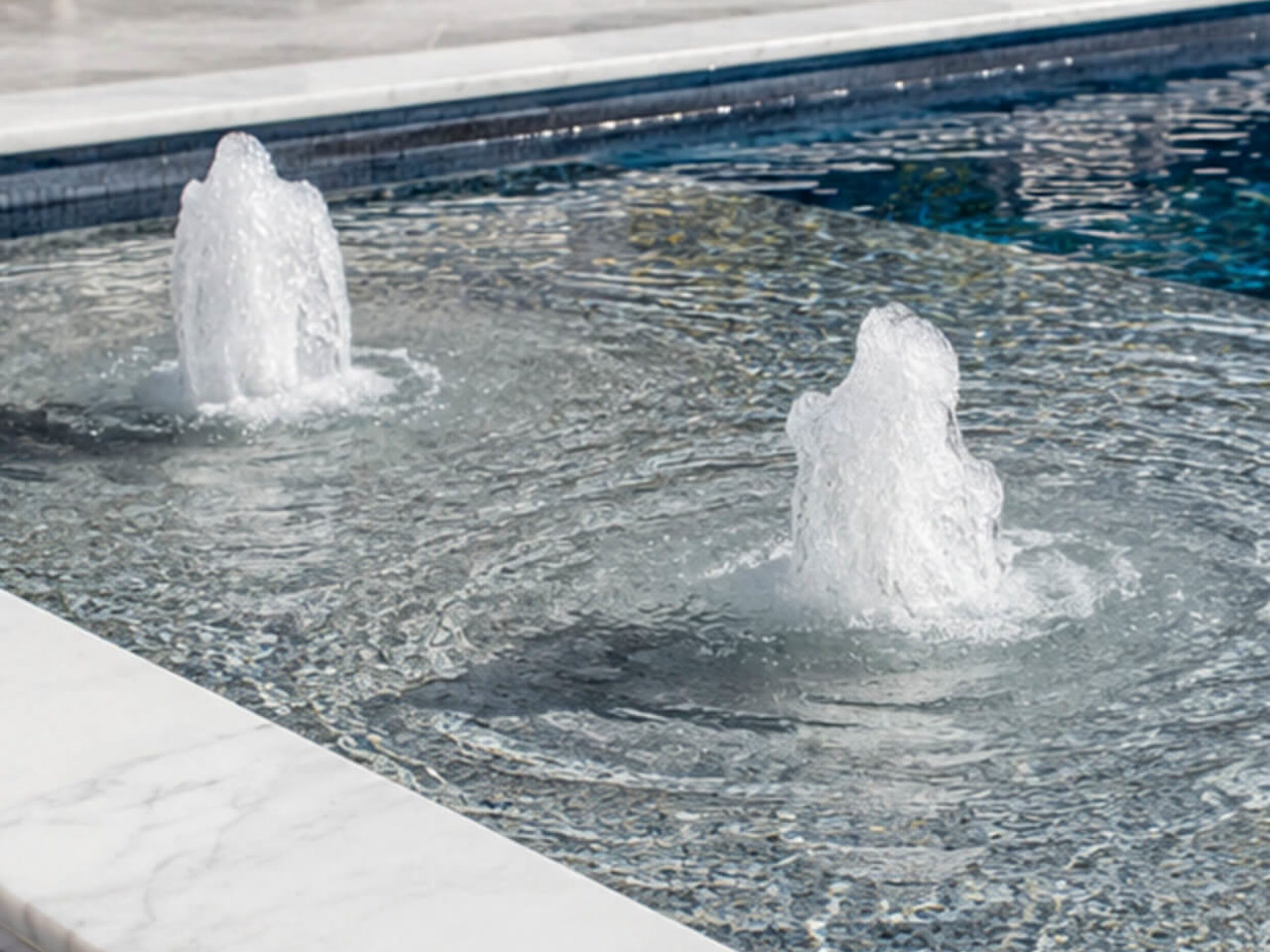 Two bubbler fountains on a mosaic tiled sun shelf edged with white marble coping for a Deerfield Beach homeowner