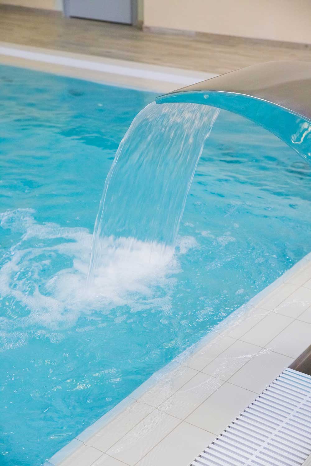 Curved stainless steel waterfall pouring into a swimming pool in Jupiter