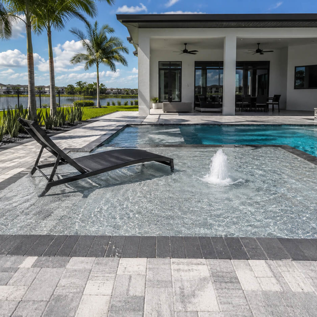 Sun shelf with a bubbler and in water lounger connecting the pool to a covered lanai at a Jupiter residence