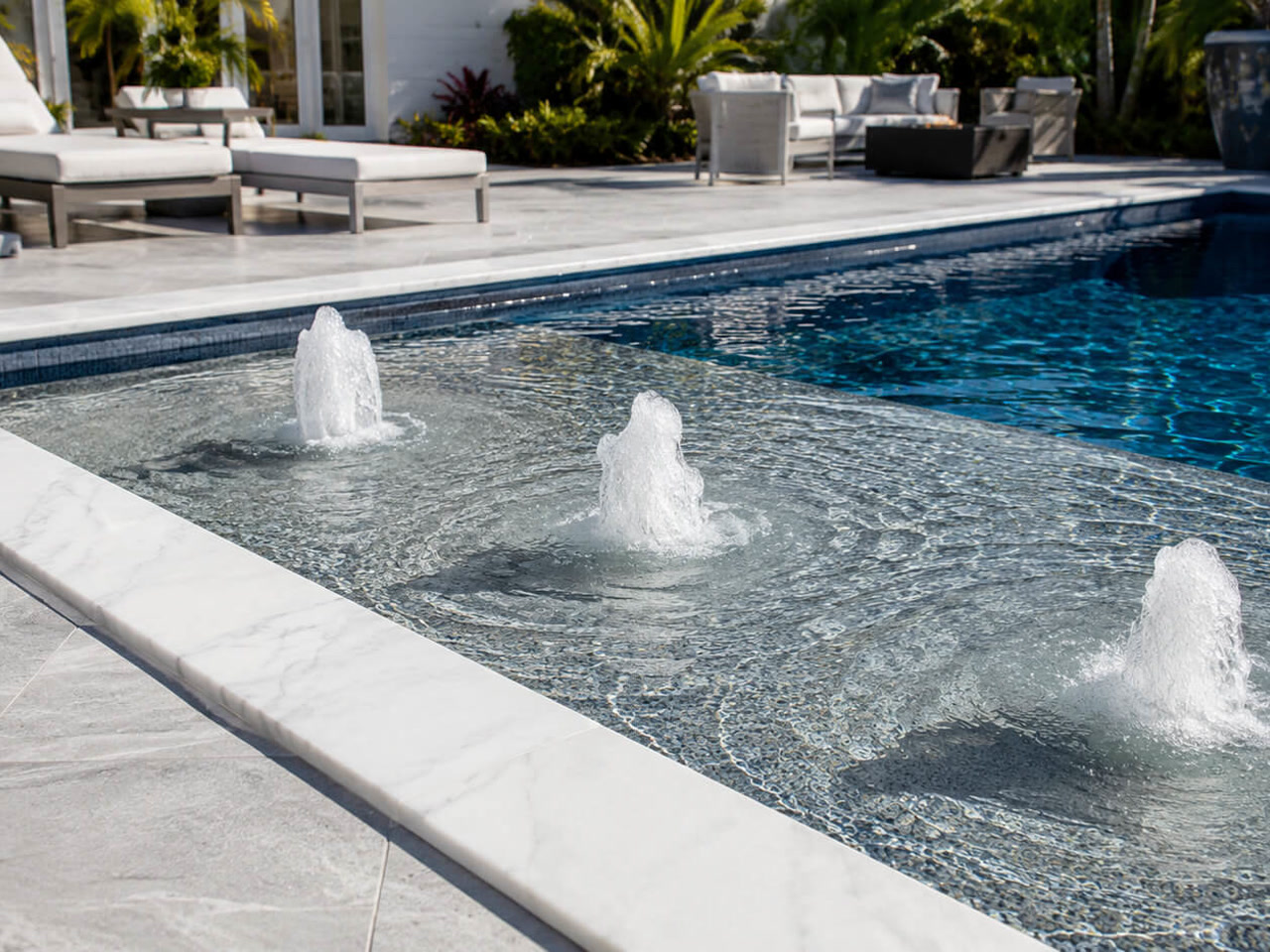 Three bubblers running across a mosaic tiled sun shelf edged in white marble coping, Palm Beach Gardens
