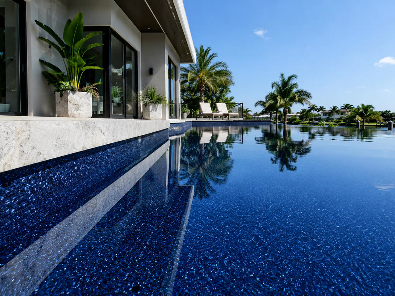 Finished pool resurfacing in a dark pebble finish, with sheer descents spilling in over gray marble coping
